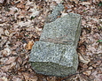 Przewrócona kamienna podstawa pod krzyż żeliwny