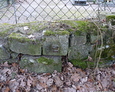 Fragmenty przedwojennych nagrobków znajdujące się w ogrodzeniu cmentarza