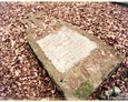 Przewrócony kamienny postument z białą tablicą inskrypcyjną (Oskowo)