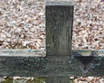 Górna część drewnianego krzyża z widoczną inskrypcją