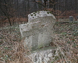 Przechylony kamienny obelisk z ,,wtopioną'' formą krzyża