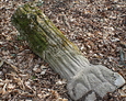 Przewrócony kamienny postument w kształcie pnia dębu