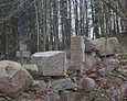 Pozostałości ściany kaplicy grobowej; w tle widoczny kamienny krzyż